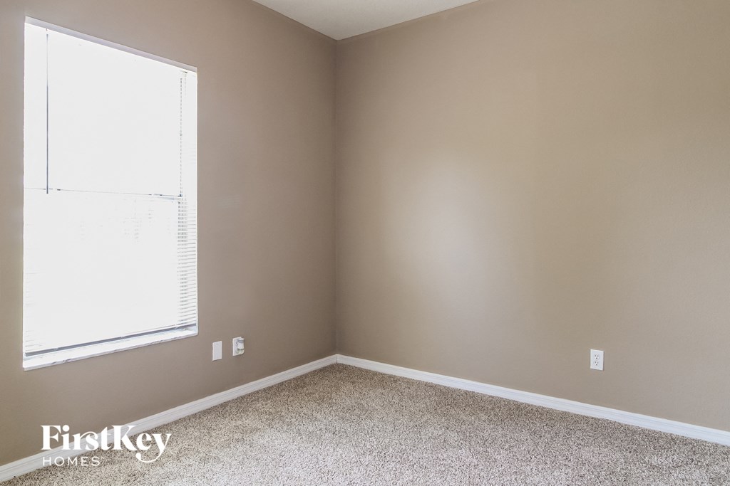 a bedroom with a window and a carpeted floor