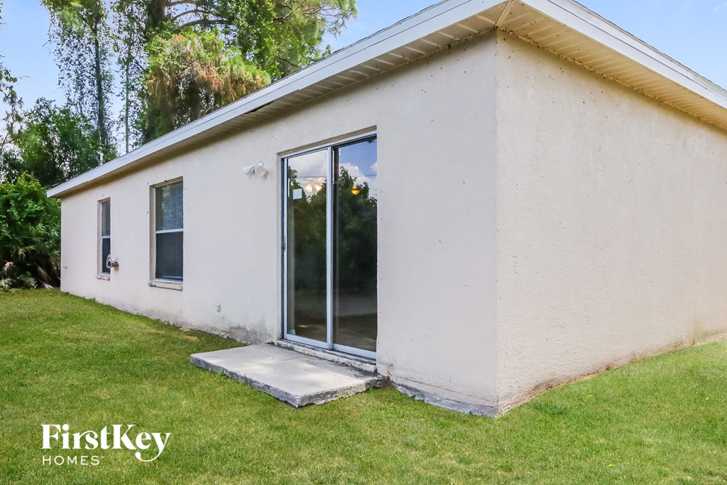 the exterior of a small white house with a sliding glass door