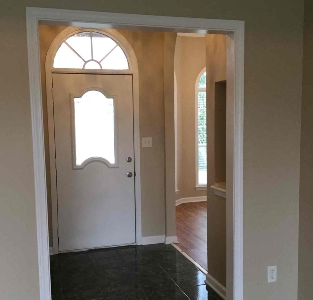 an empty room with a white door and a window