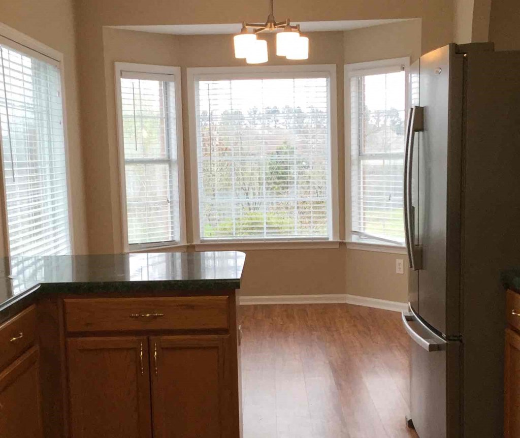 an empty kitchen with a large window and a refrigerator