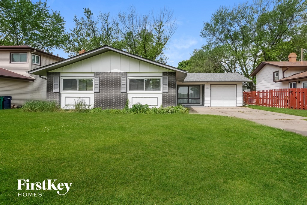 A house with a green lawn in front of it.