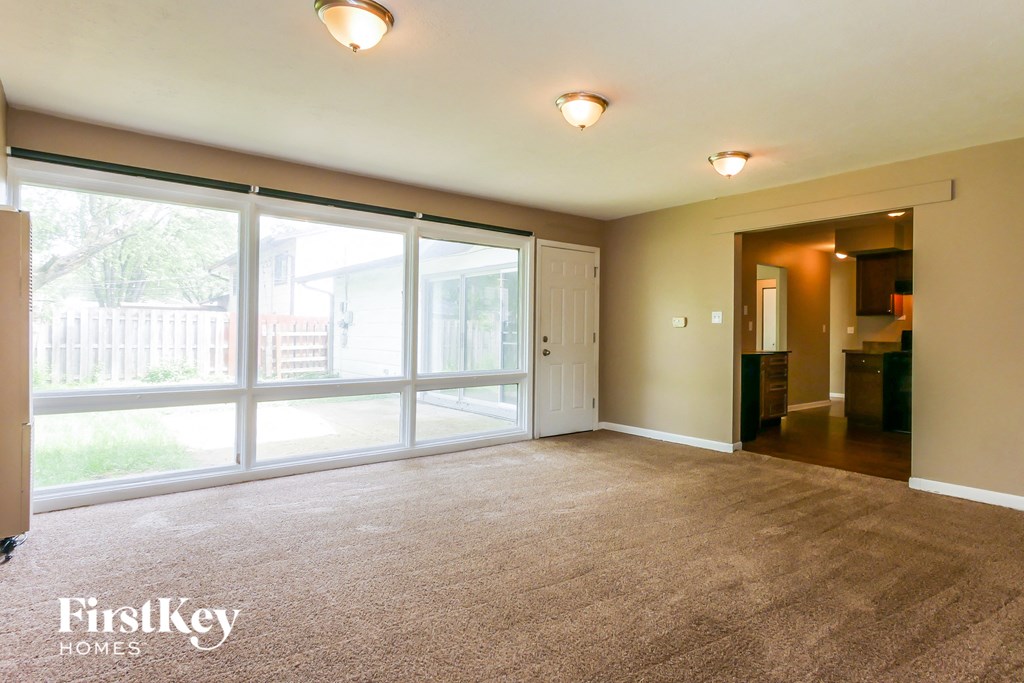 A spacious room with a carpeted floor and sliding glass doors.