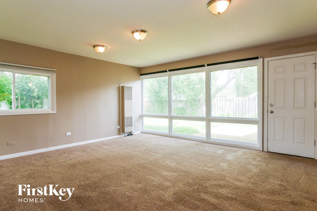 A spacious room with a carpeted floor and sliding glass doors leading to a backyard.
