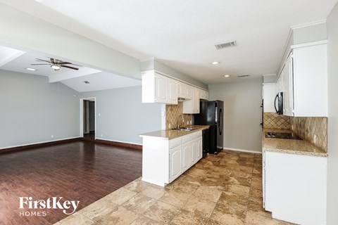 A kitchen with a black refrigerator and white cabinets.