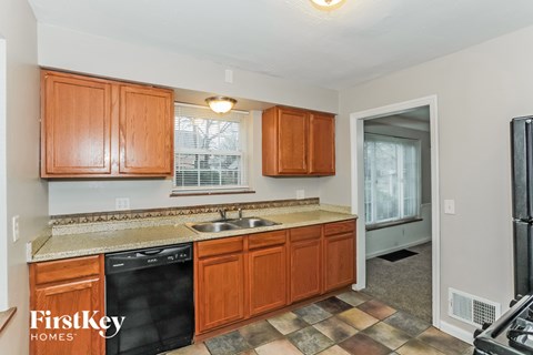 A kitchen with wooden cabinets and a black dishwasher.