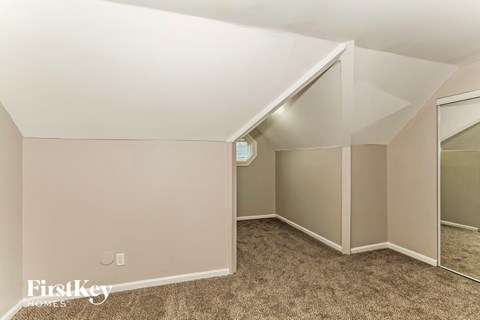 A bedroom with a carpeted floor and a mirror on the wall.
