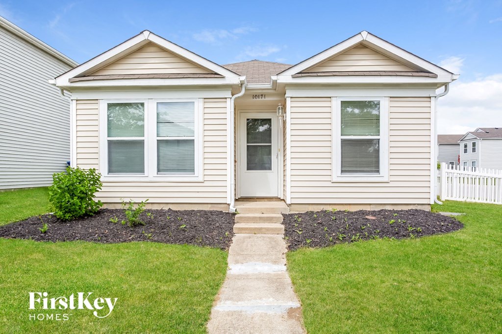 the front of a white house with a lawn and grass