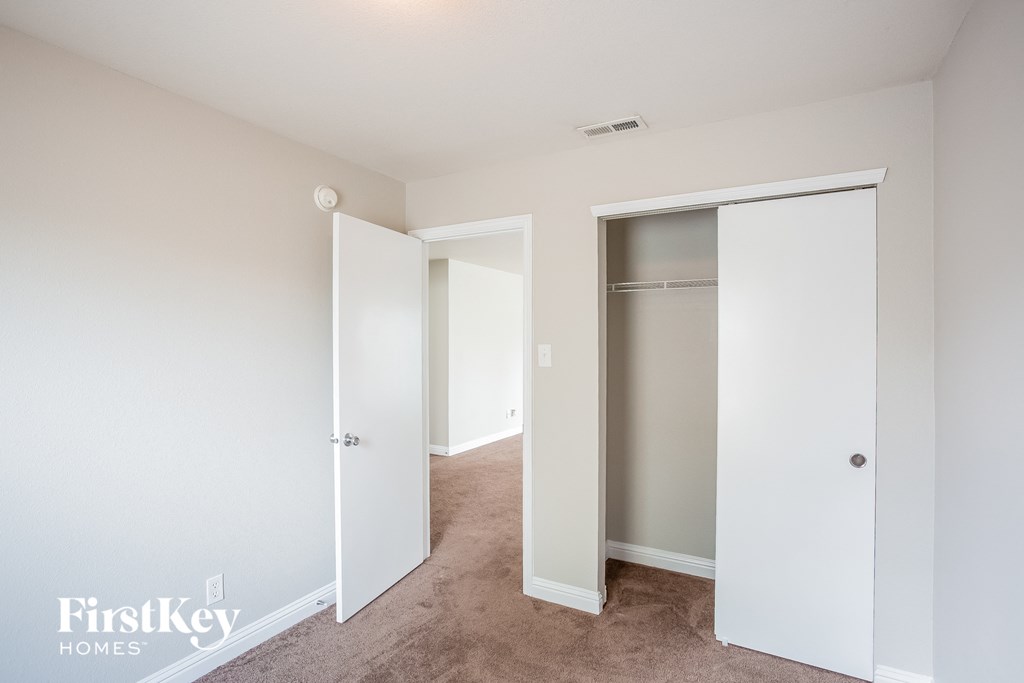 a bedroom with white closets and carpeting and white doors
