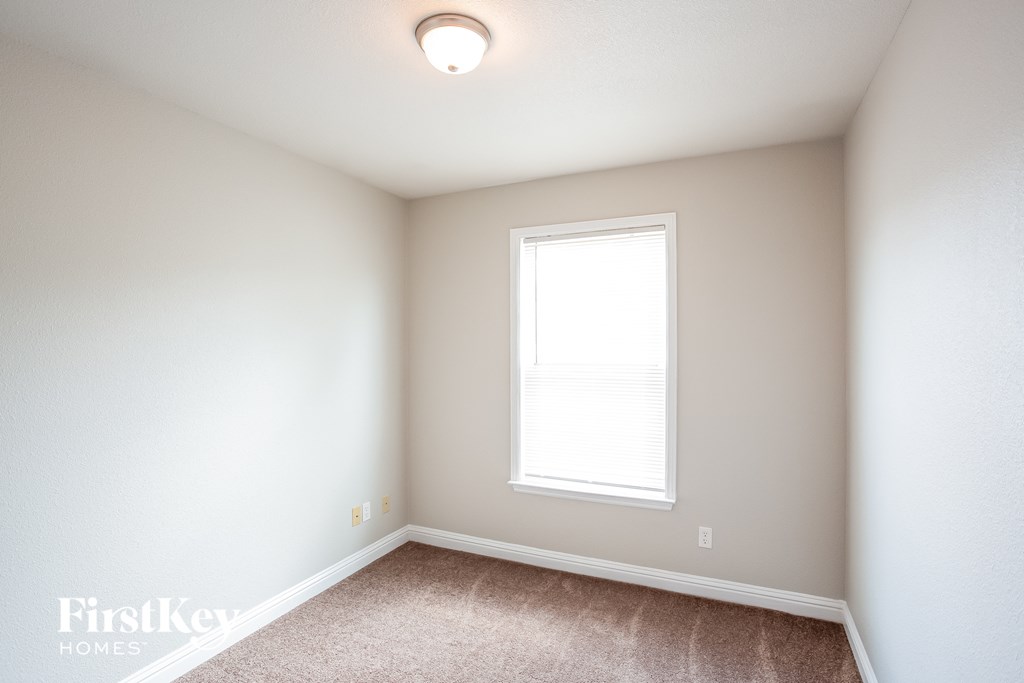 a bedroom with white walls and a window and carpet