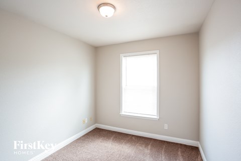 a bedroom with white walls and a window and carpet