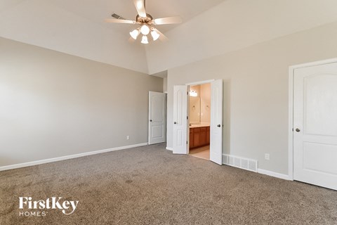 a spacious living room with carpet and a ceiling fan