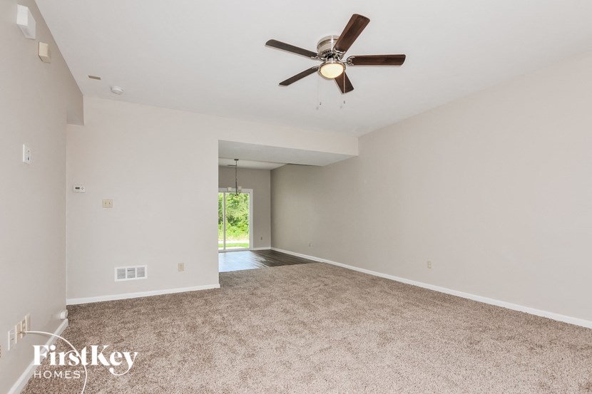 an empty living room with a ceiling fan