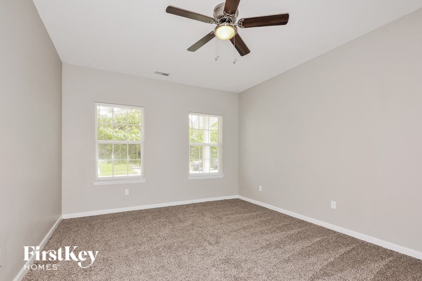 an empty room with a ceiling fan and two windows
