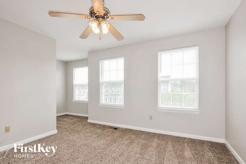 a living room with a ceiling fan and three windows
