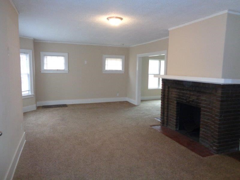 an empty living room with a brick fireplace