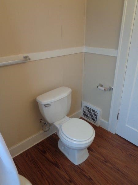 a small bathroom with a toilet and a wooden floor