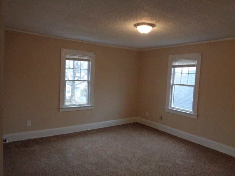 an empty room with two windows and a ceiling light