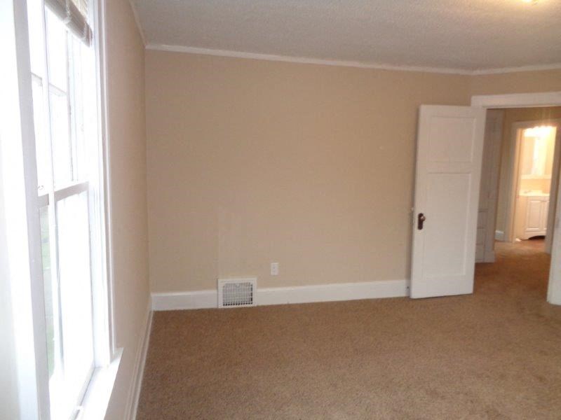 an empty living room with a door to a bedroom