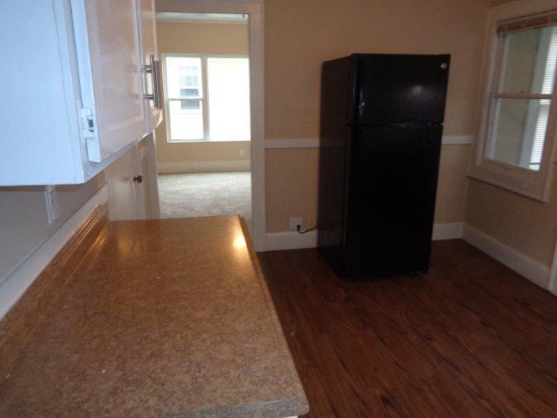 an empty kitchen with a black refrigerator in it