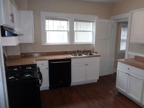 a kitchen with white cabinets and a black stove and sink