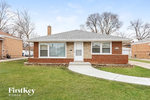 a small brick house with a sidewalk in front of it