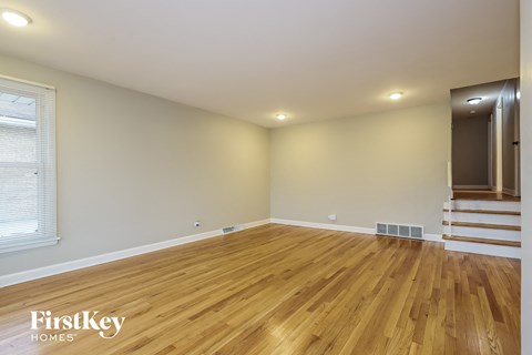 the living room of an empty house with wooden floors and stairs