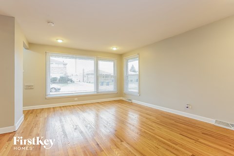 an empty living room with wood floors and large windows