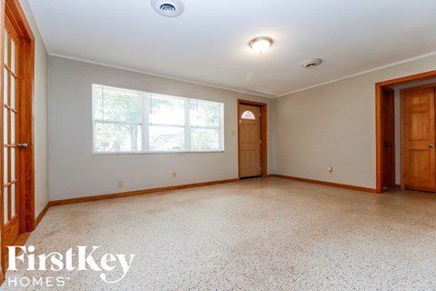 A spacious room with a large window and a door on the right side.