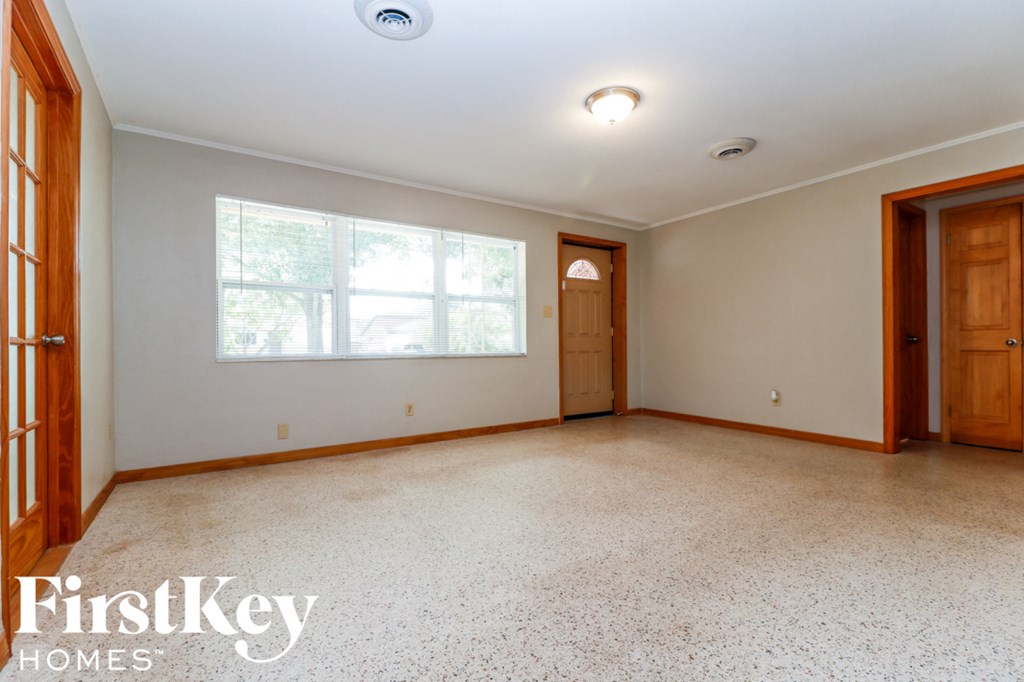 A spacious room with a large window and a door on the right side.