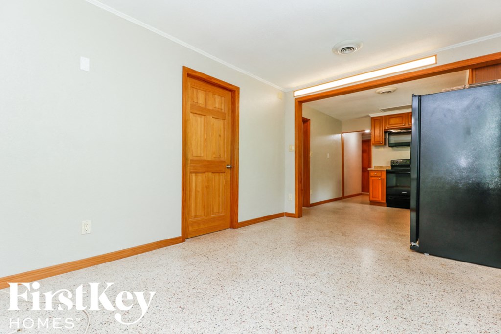 A room with a black refrigerator and wooden doors.