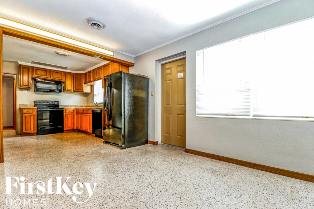 A kitchen with a refrigerator, microwave, and oven.