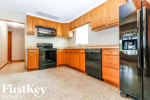 A kitchen with wooden cabinets and a black fridge.