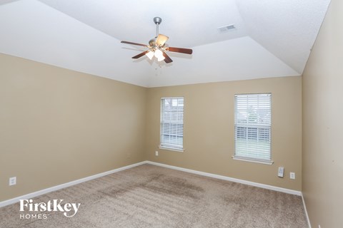 a living room with a ceiling fan and a carpet