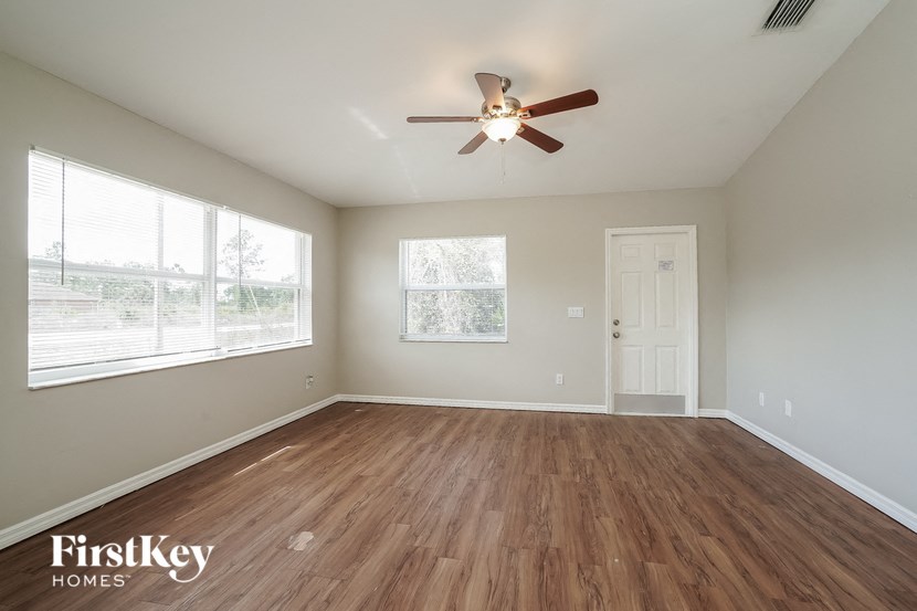 A room with a ceiling fan and wooden flooring.