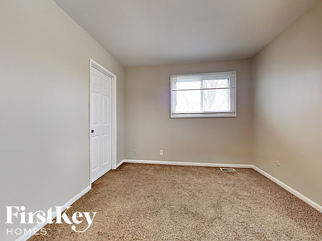 a bedroom with carpet and a window and a white door