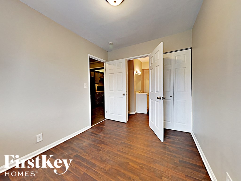 an empty bedroom with wood flooring and white doors