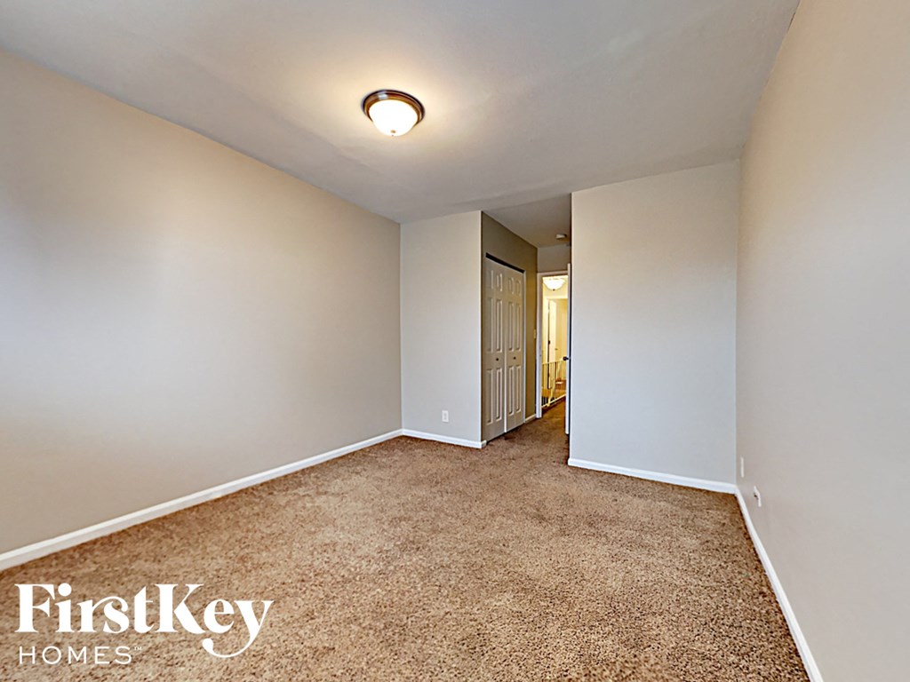 a bedroom with a carpeted floor and white walls and a door to a hallway