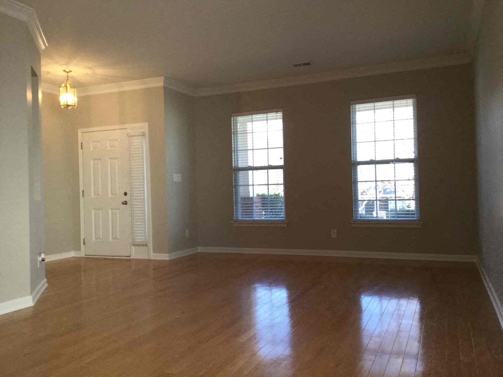A room with wooden floors and two windows.