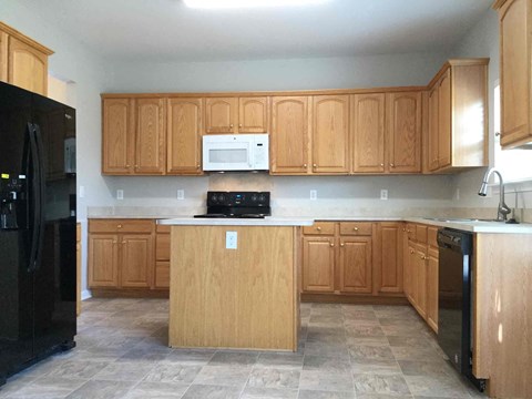 A kitchen with wooden cabinets and a black refrigerator.