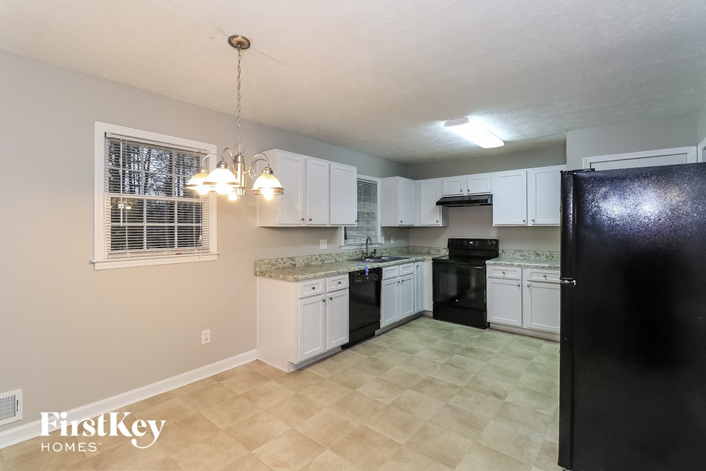 A kitchen with black appliances and white cabinets.