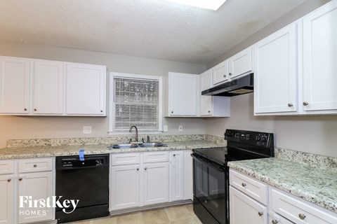 A kitchen with black appliances and white cabinets.