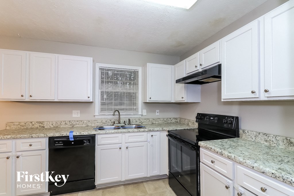 A kitchen with black appliances and white cabinets.