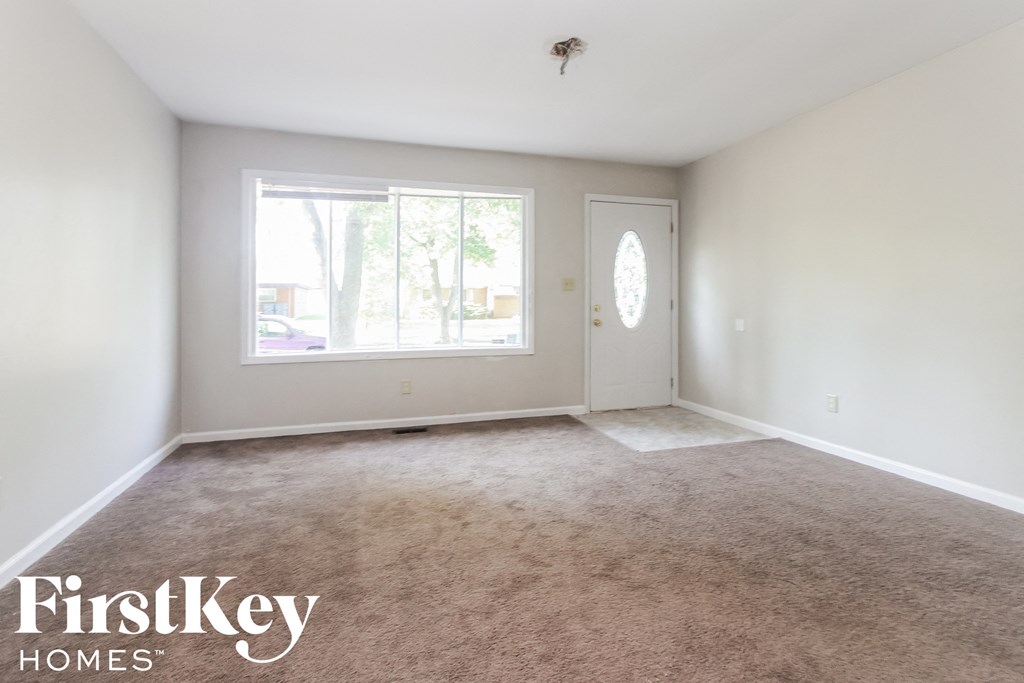 an empty living room with a large window and carpet