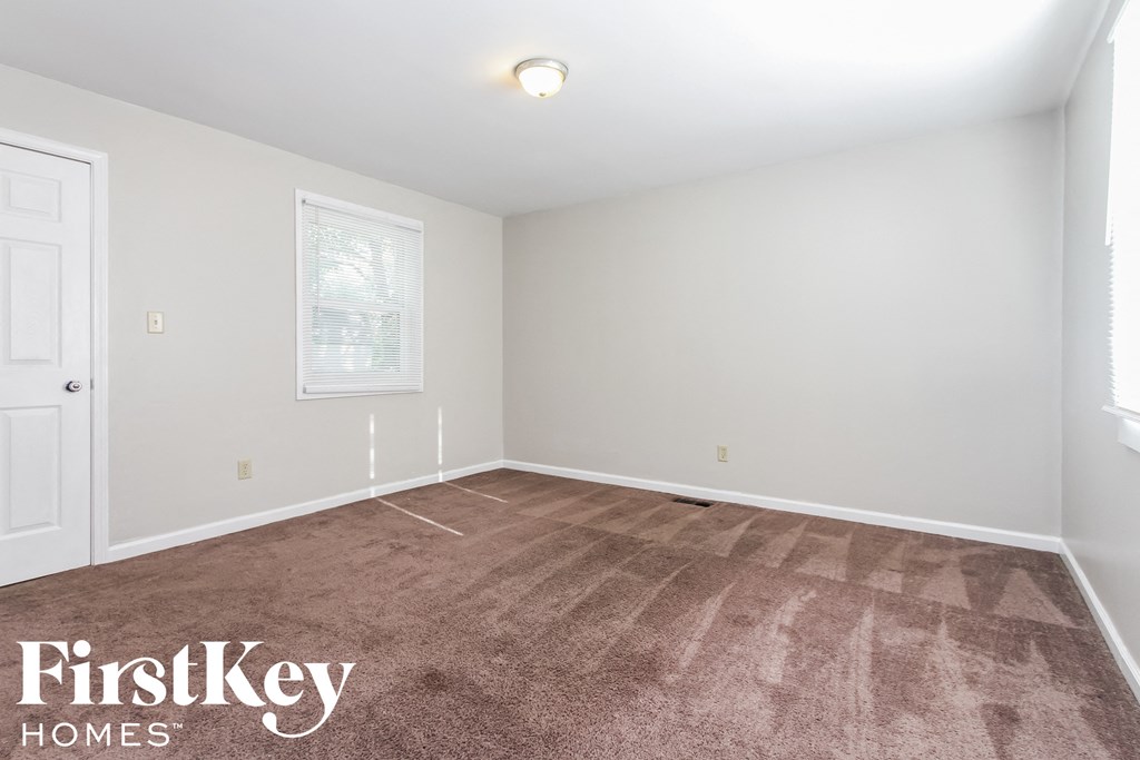 a bedroom with a carpeted floor and white walls and a window