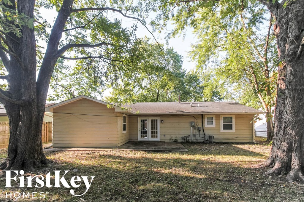 a small tan house with a yard and trees