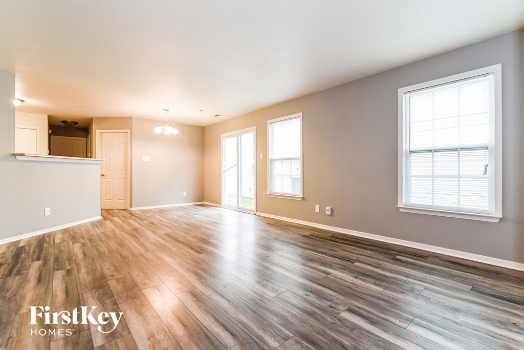 the living room and kitchen of an empty house with wood flooring