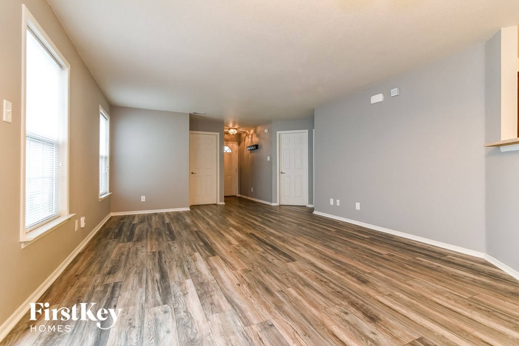the living room and dining room of an empty house with wood flooring