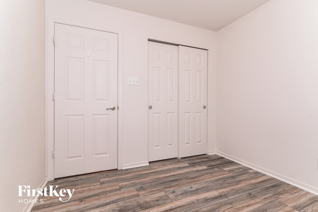 the living room of a home with white doors and wood floors