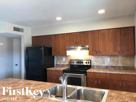 A kitchen with a black fridge and stove top oven.