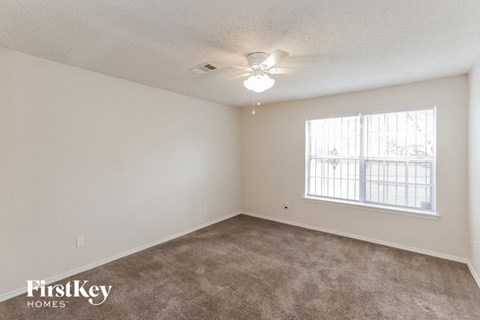a spacious living room with carpet and a ceiling fan